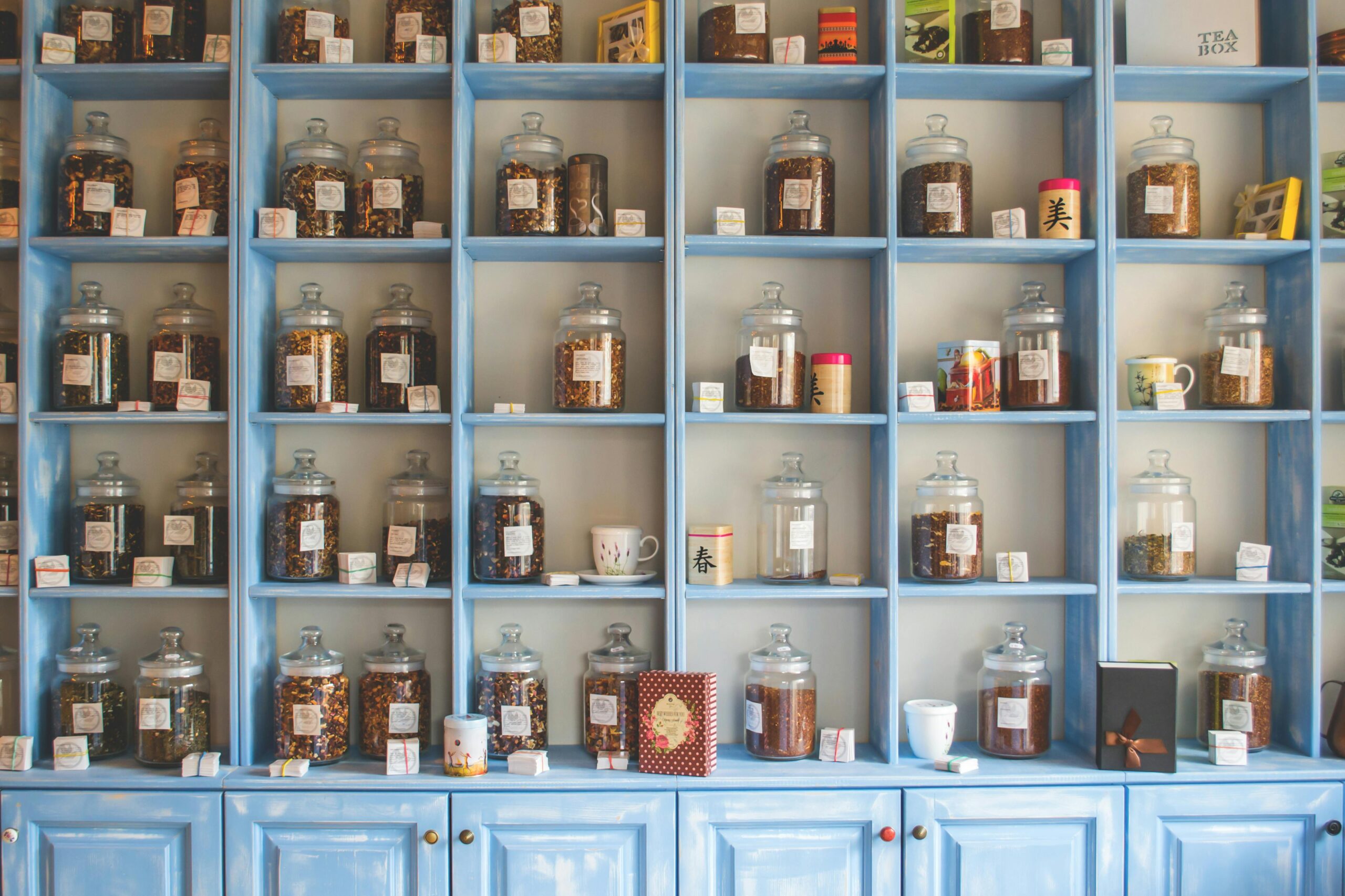 Organized display of herbal tea jars on vibrant blue shelves in a shop.